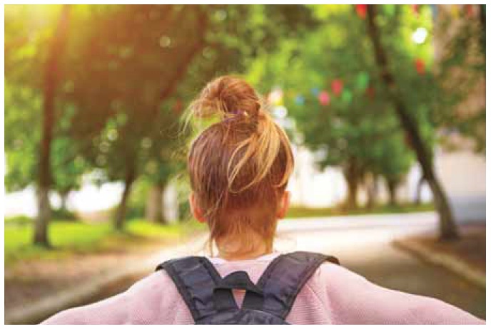 Description de l'image par IA : Femme marchant dans une rue bordée d'arbres, vue de dos, portant un sac à dos.